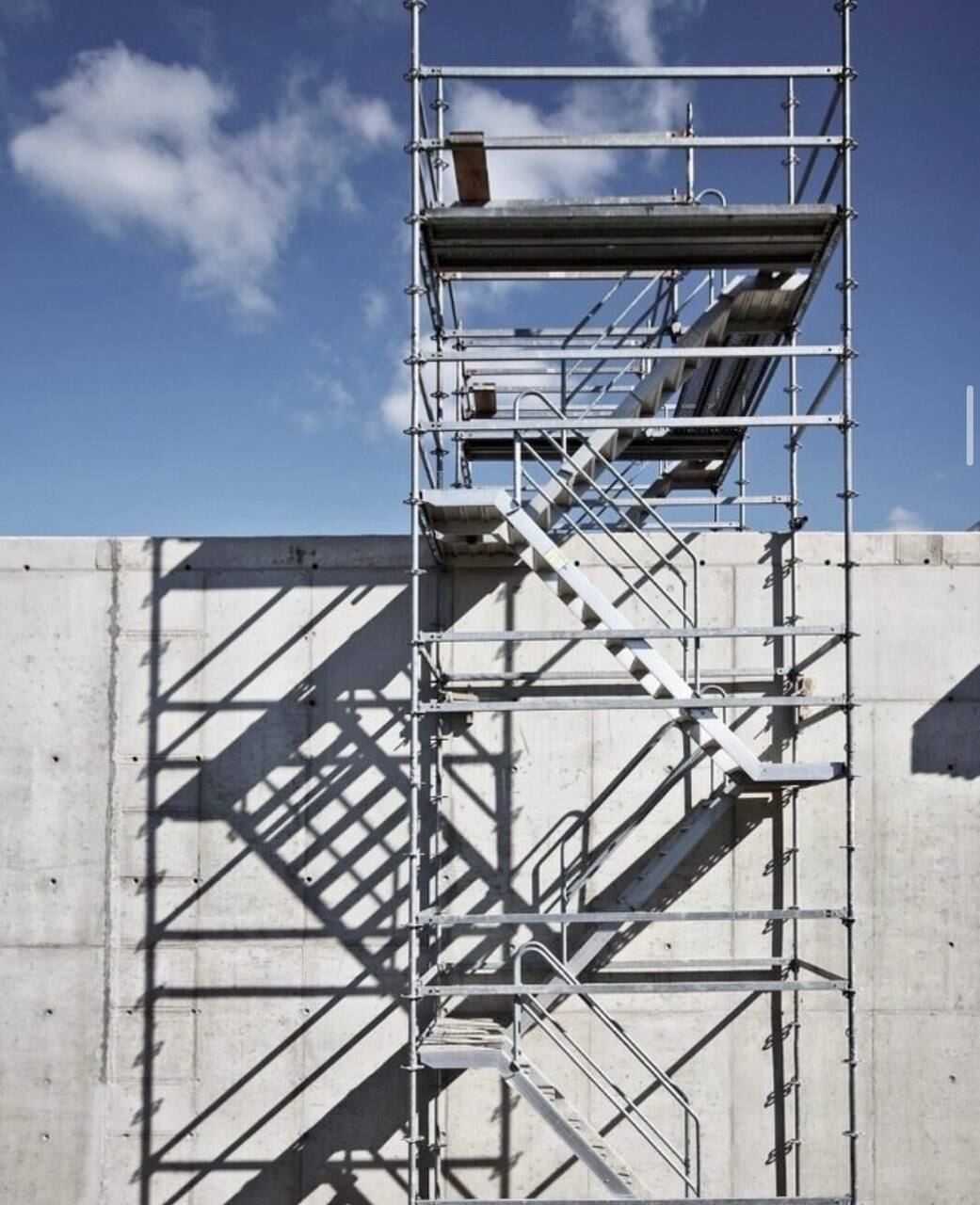 Scaffold staircase tower against a concrete wall